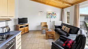 A modern kitchen with a TV, wooden cabinets, and a dining area with a table and chairs. - Am Sonnenblick, Whg. 6:41 m² apartment with balcony, WLAN & close to the beach (Heringsdorf)
