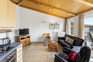 A modern kitchen with a TV, wooden cabinets, and a dining area with a table and chairs.