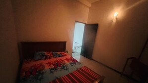 Une chambre à coucher avec un lit, une table de chevet et une lampe fixée au mur.