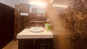 Une salle de bain avec un lavabo blanc, des murs en marbre foncé et un miroir au-dessus.