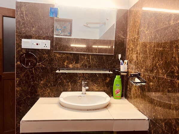 A bathroom with a white sink, a mirror, a towel rack, and a green bottle of shampoo.