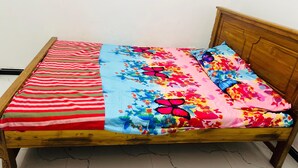 Un lit en bois avec une couverture à rayures et une couette à motifs floraux.