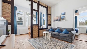 Un salon moderne avec un canapé gris, des coussins bleus, une table basse en bois et un tapis à motifs.