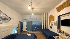 Hotellihuone, jossa on kaksi sänkyä, televisio ja kirjahylly.