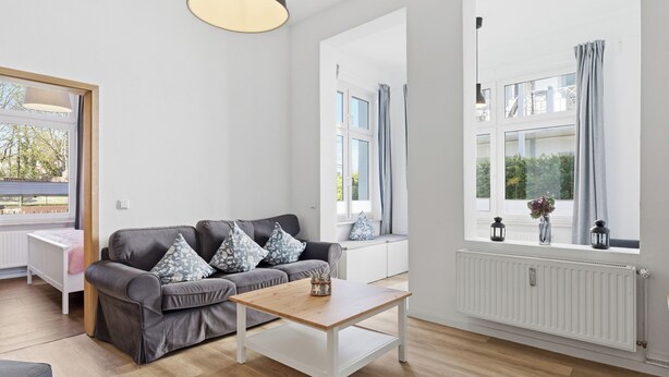 Un salon moderne avec un canapé gris, une table basse en bois et un radiateur blanc.