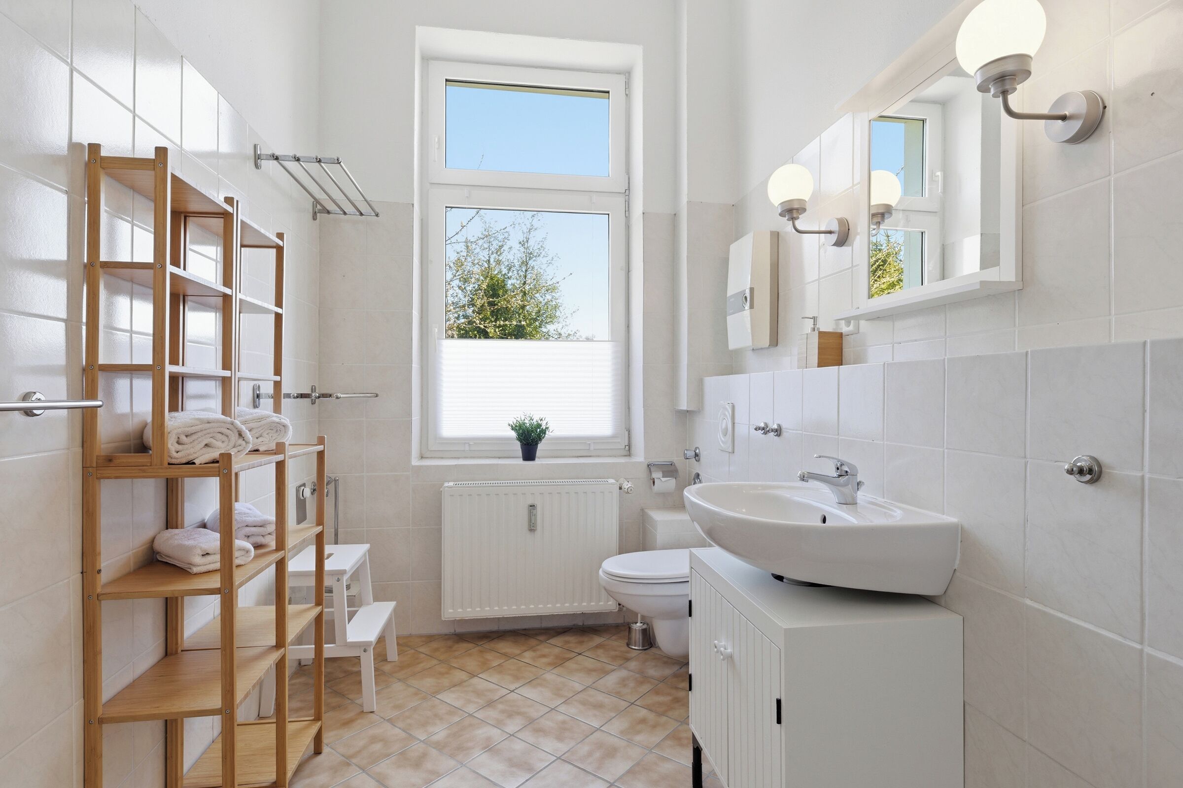 Een moderne badkamer met een houten plank, een raam, een radiator, een toilet en een wastafel.