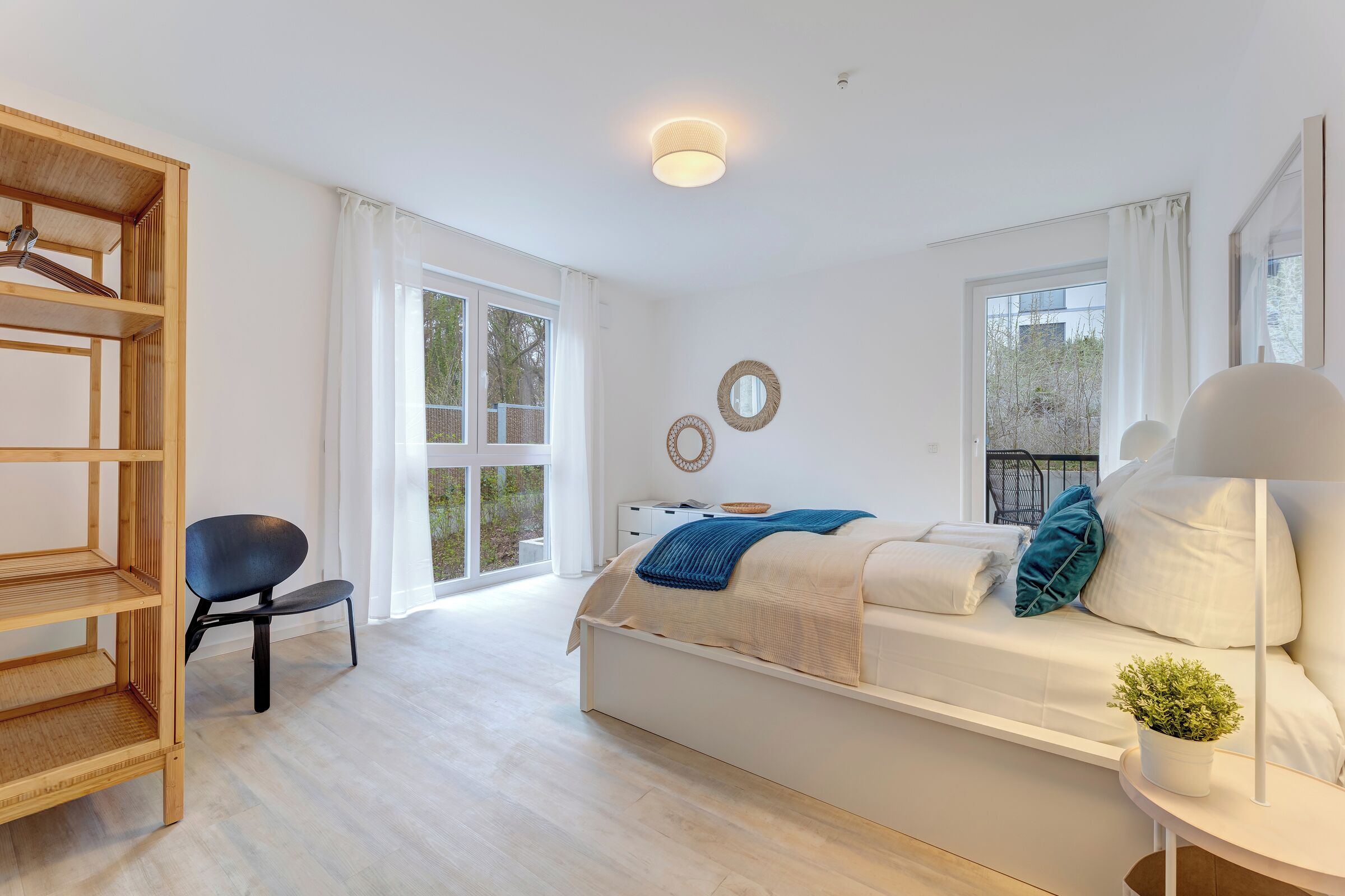 Un dormitorio moderno con una cama, un estante de madera, una silla y una planta en maceta.