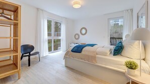Une chambre moderne avec un lit, une étagère en bois, une chaise et une plante en pot.