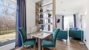 Una sala moderna con una mesa de madera, dos sillas color aguamarina, un sofá y una estantería.