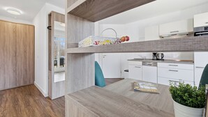 Una cocina moderna con armarios blancos, encimera de madera y un colgador para ollas.