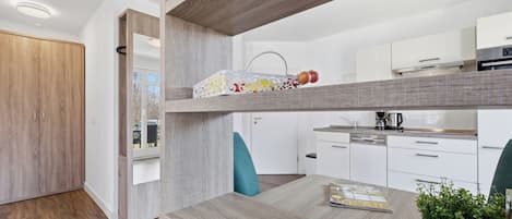 A modern kitchen with white cabinets, a wooden countertop, and a hanging pot rack.