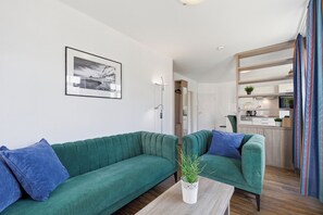 Un salon moderne avec deux canapés verts, une table basse et un tableau encadré accroché au mur.