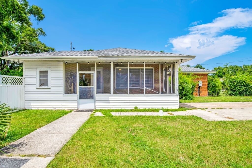 Une maison de plain-pied avec un porche à l’avant, un petit garage attenant et une pelouse bien entretenue.