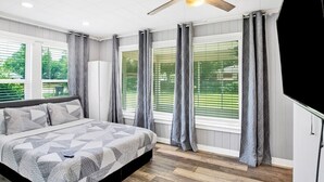 A bedroom with a bed, a ceiling fan, and large windows with curtains. - These units are in the highly sought after Pensacola Heights neighborhood. (Pensacola)