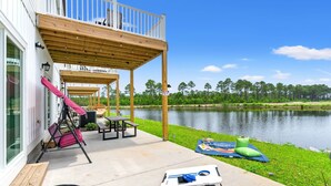 A covered outdoor deck with a swing set, picnic table, and kayak storage. - Luxury waterfront retreat-Near golf Beach Barefoot (Longs)