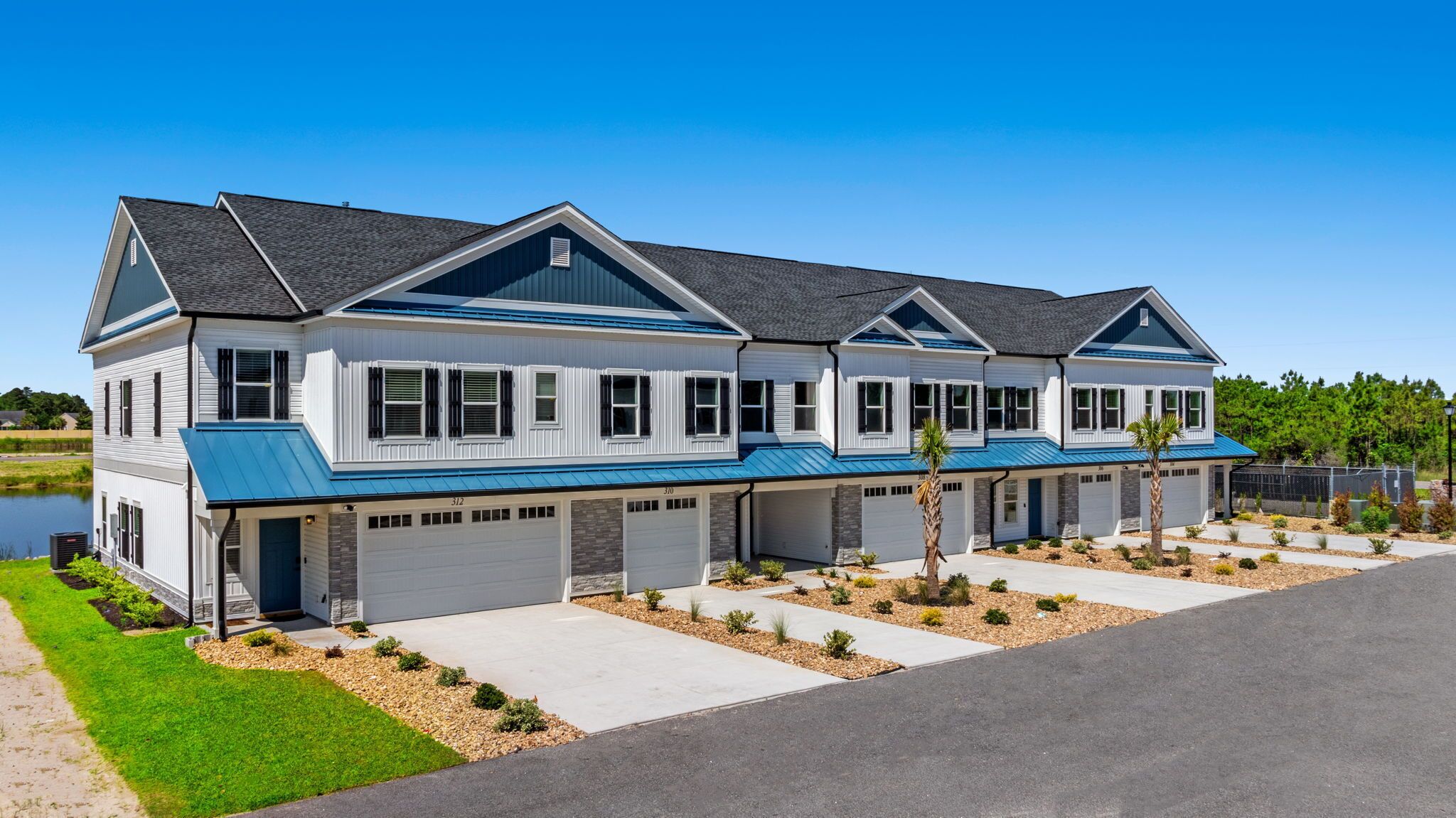 A modern two-story residential building with a blue roof and white siding.