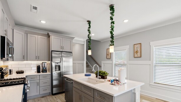 A modern kitchen with white cabinets, stainless steel appliances, and a central island.