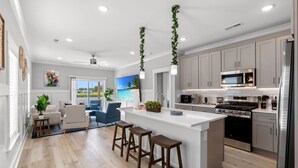 A modern kitchen with a central island, stainless steel appliances, and a large window.