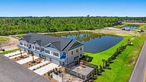 A large, modern house with a spacious front yard and a small pond.