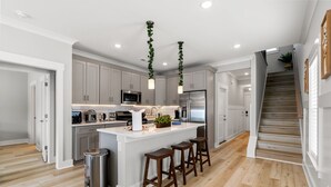 A modern kitchen with grey cabinets, stainless steel appliances, and a central island with stools.