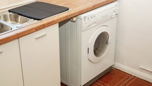 Un espace buanderie compact comprenant un lave-linge, un évier et un plan de travail en bois.