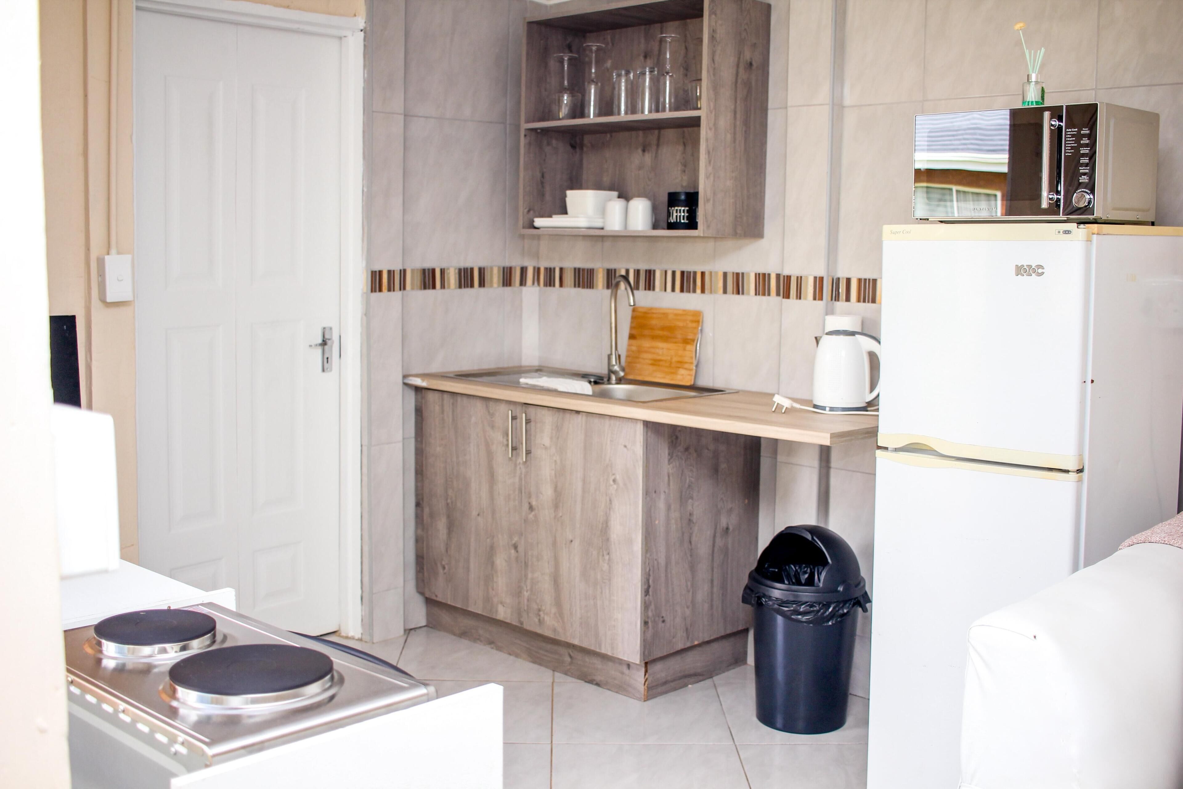 A compact kitchen with a microwave, a coffee maker, and a trash bin.