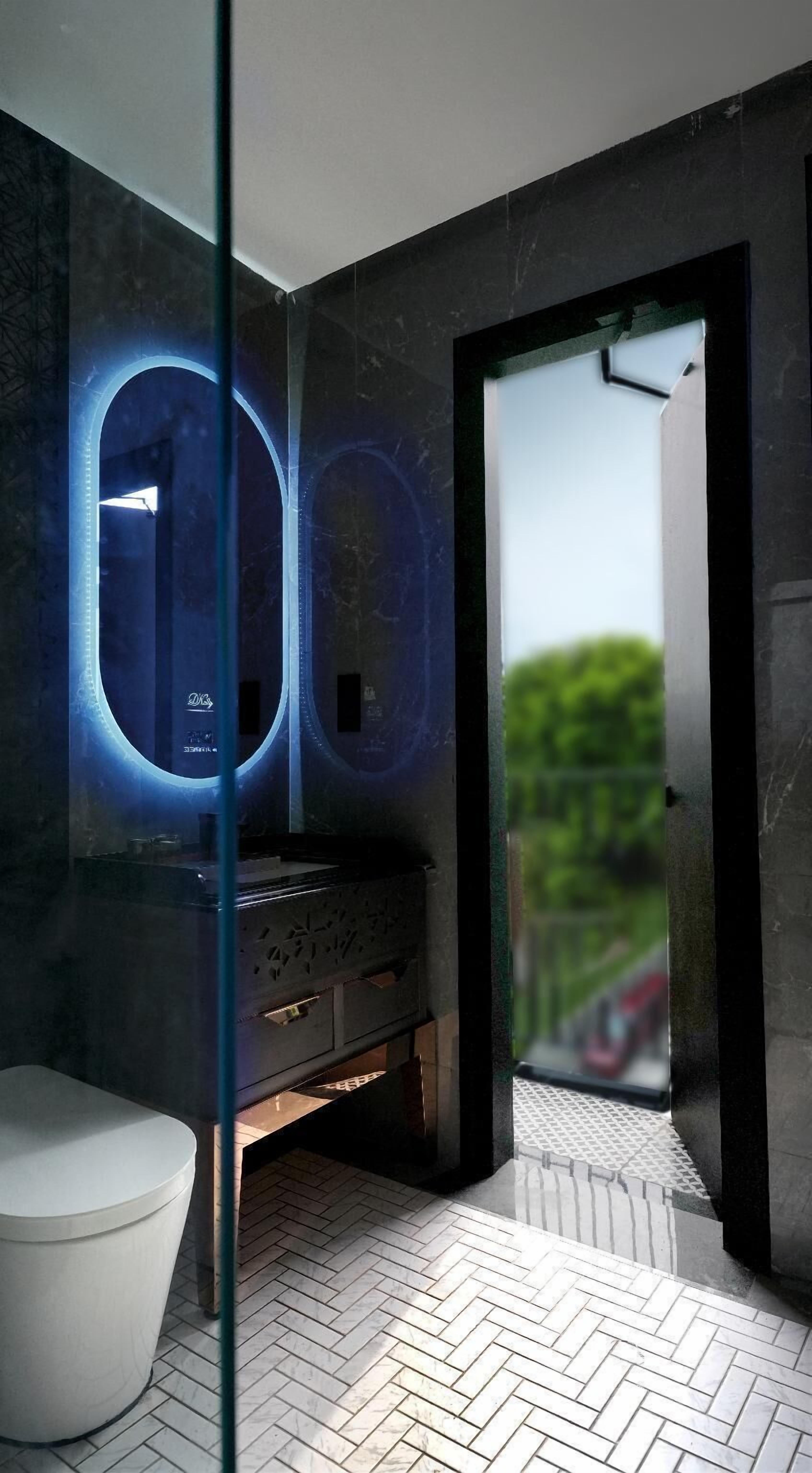 Ein modernes Badezimmer mit Glasabtrennung, einem weißen Waschbecken und einem Spiegel mit LED-Beleuchtung.