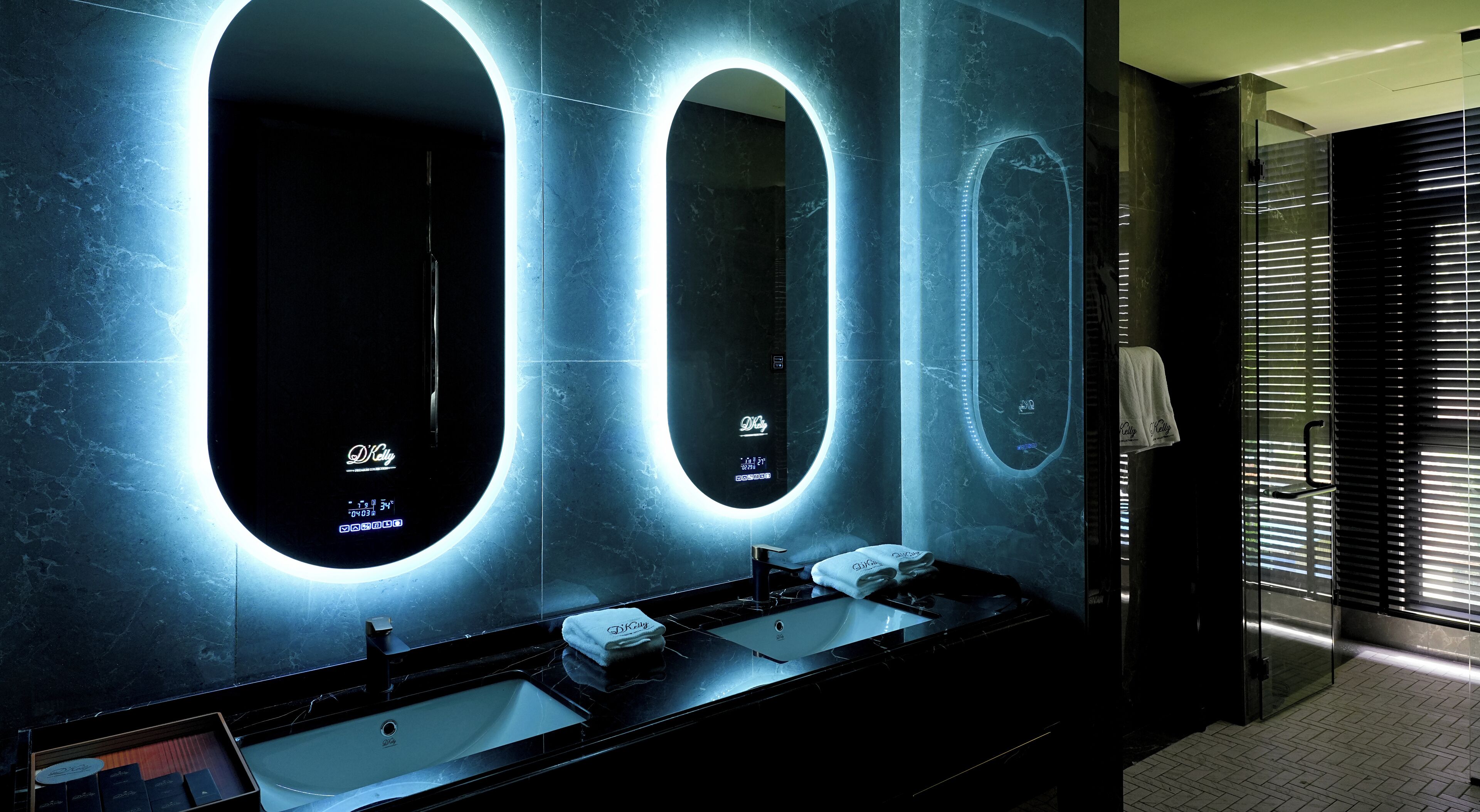 A modern bathroom with three sinks, each with a mirror and illuminated by a circular light.