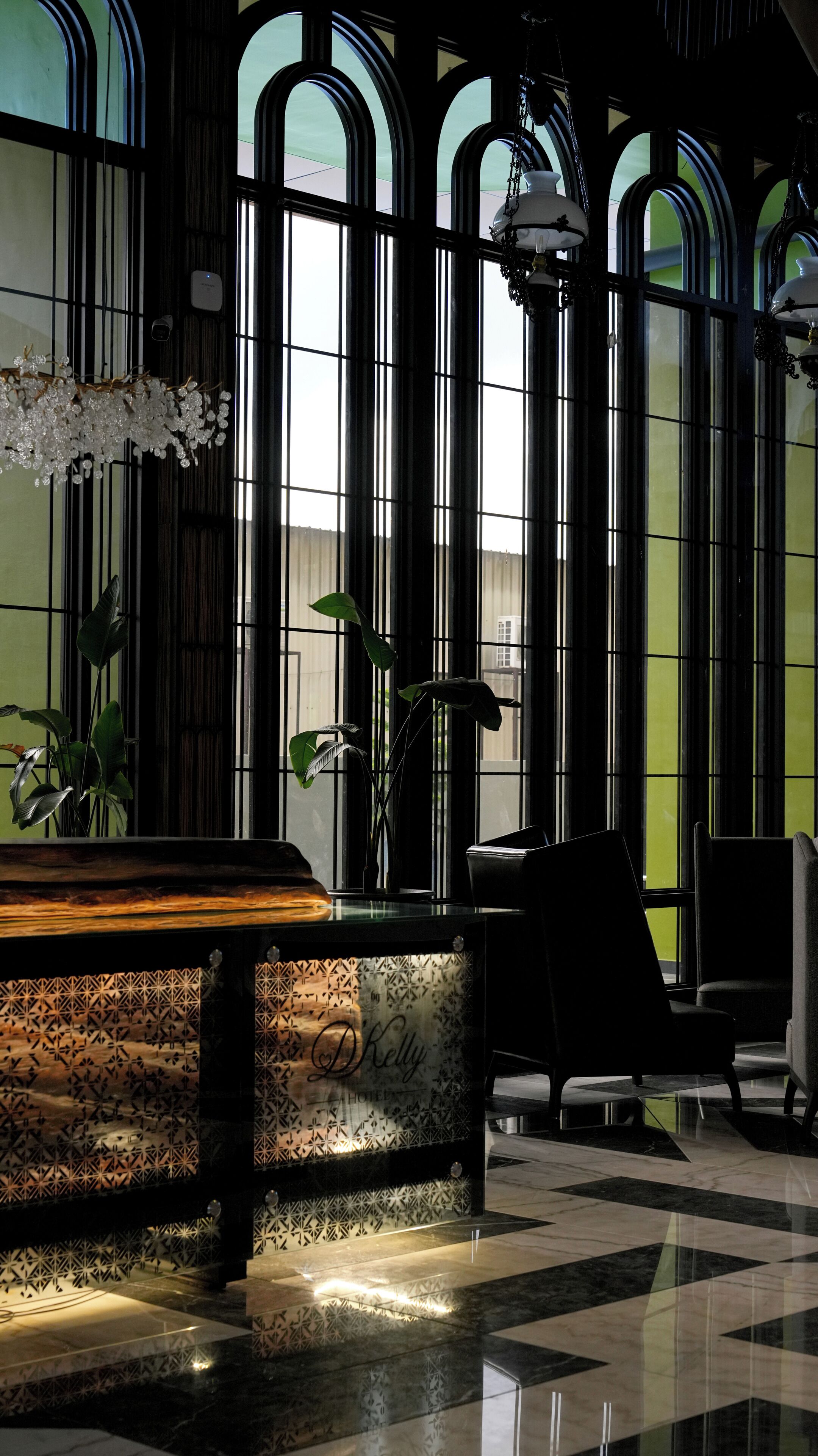 Un vestíbulo con mostrador de recepción, amplias ventanas arqueadas y un candelabro.
