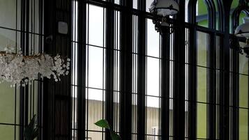 Un vestíbulo con mostrador de recepción, amplias ventanas arqueadas y un candelabro.