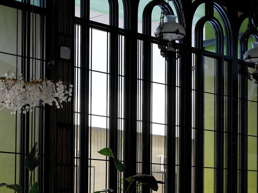 Un vestíbulo con mostrador de recepción, amplias ventanas arqueadas y un candelabro.