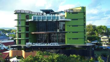 A modern hotel with a green facade, multiple balconies, and a sign reading "1969 D'KELLY HOTEL".
