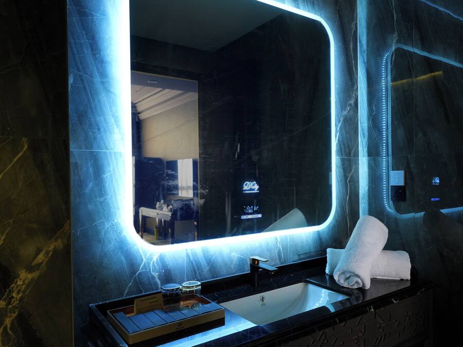 A modern bathroom with a large mirror, a sink, and a towel rack.