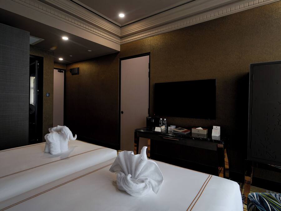 A hotel room with two beds, a flat-screen TV, a desk with a coffee maker, and a wardrobe.