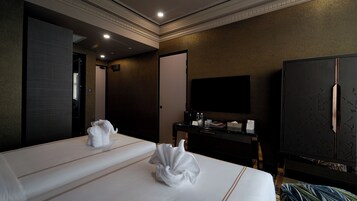 A hotel room with two beds, a flat-screen TV, a desk with a coffee maker, and a wardrobe.