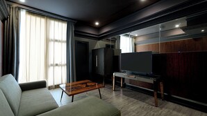 A modern living room with a sofa, a coffee table, a TV, and a wooden cabinet. - 1969 DKelly Hotel  (Ipoh)