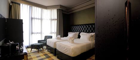 A hotel room with a large bed, two bedside tables, a chair, a TV, and a wardrobe.