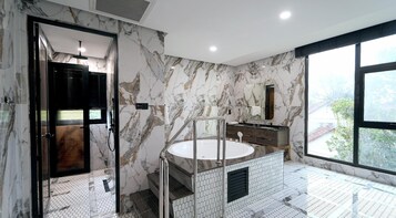Un baño con pared de mármol, un lavamanos con espejo y una ventana con vistas.