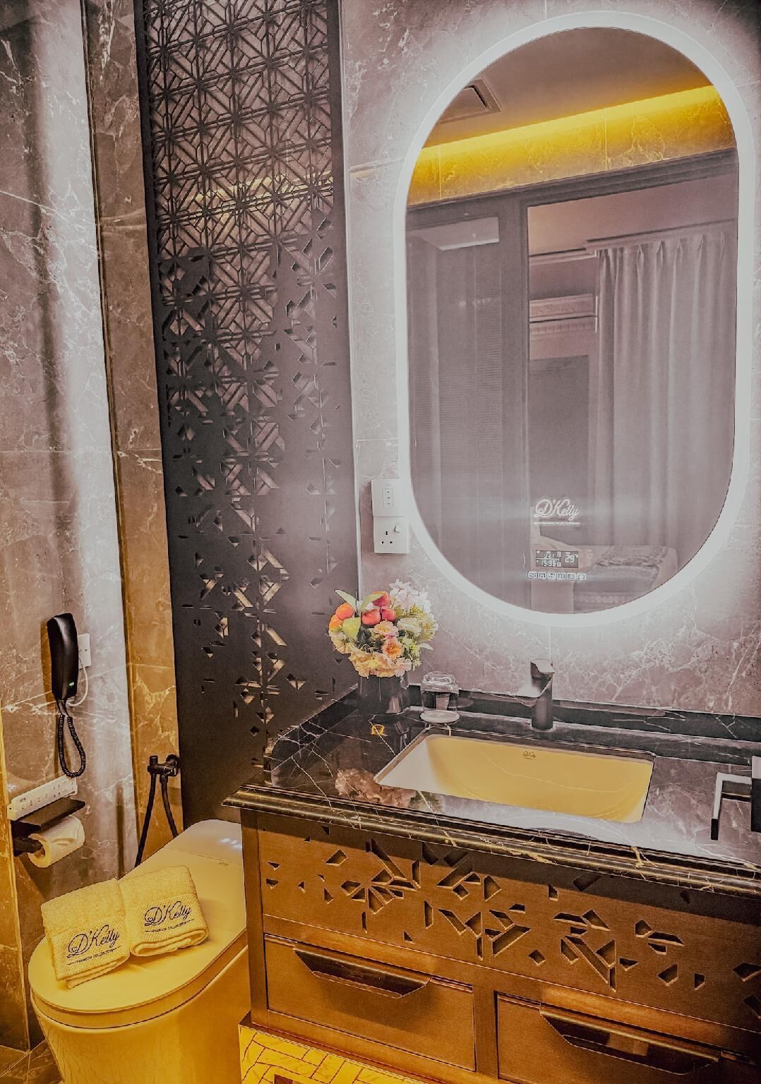 Een badkamer met een marmeren wastafel, een ronde spiegel en een toilet met handdoeken.