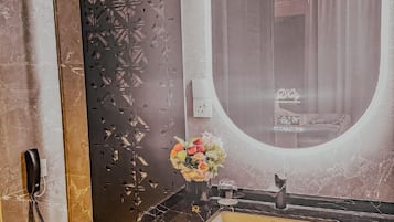 A bathroom with a marble vanity, a round mirror, and a toilet with towels.