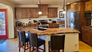 A kitchen with wooden cabinets, a central island with bar stools, stainless steel appliances, and pendant lighting. - Upscale Family Mountain Cabin ~Deck w/ views + Fire Table ~Game Room (Flagstaff)