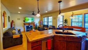 A spacious kitchen with a wooden island, a fireplace, and a dining area with a large table. - Upscale Family Mountain Cabin ~Deck w/ views + Fire Table ~Game Room (Flagstaff)