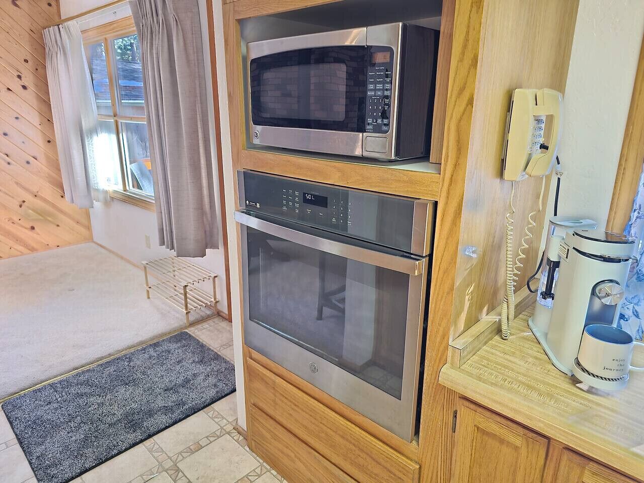 Una cucina compatta con forno a microonde, forno e macchina da caffè.