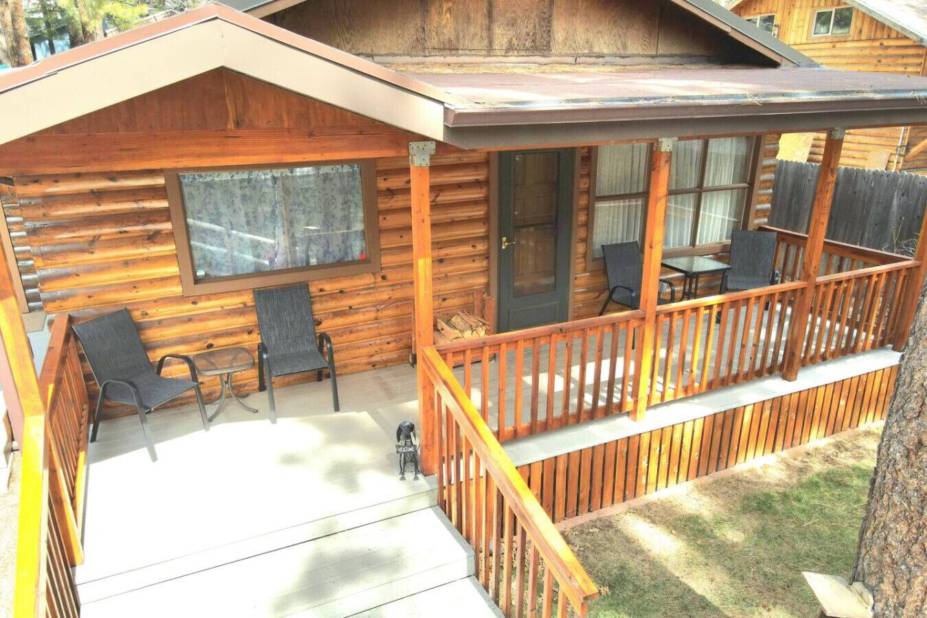 A wooden cabin with a porch, two chairs, and a table.