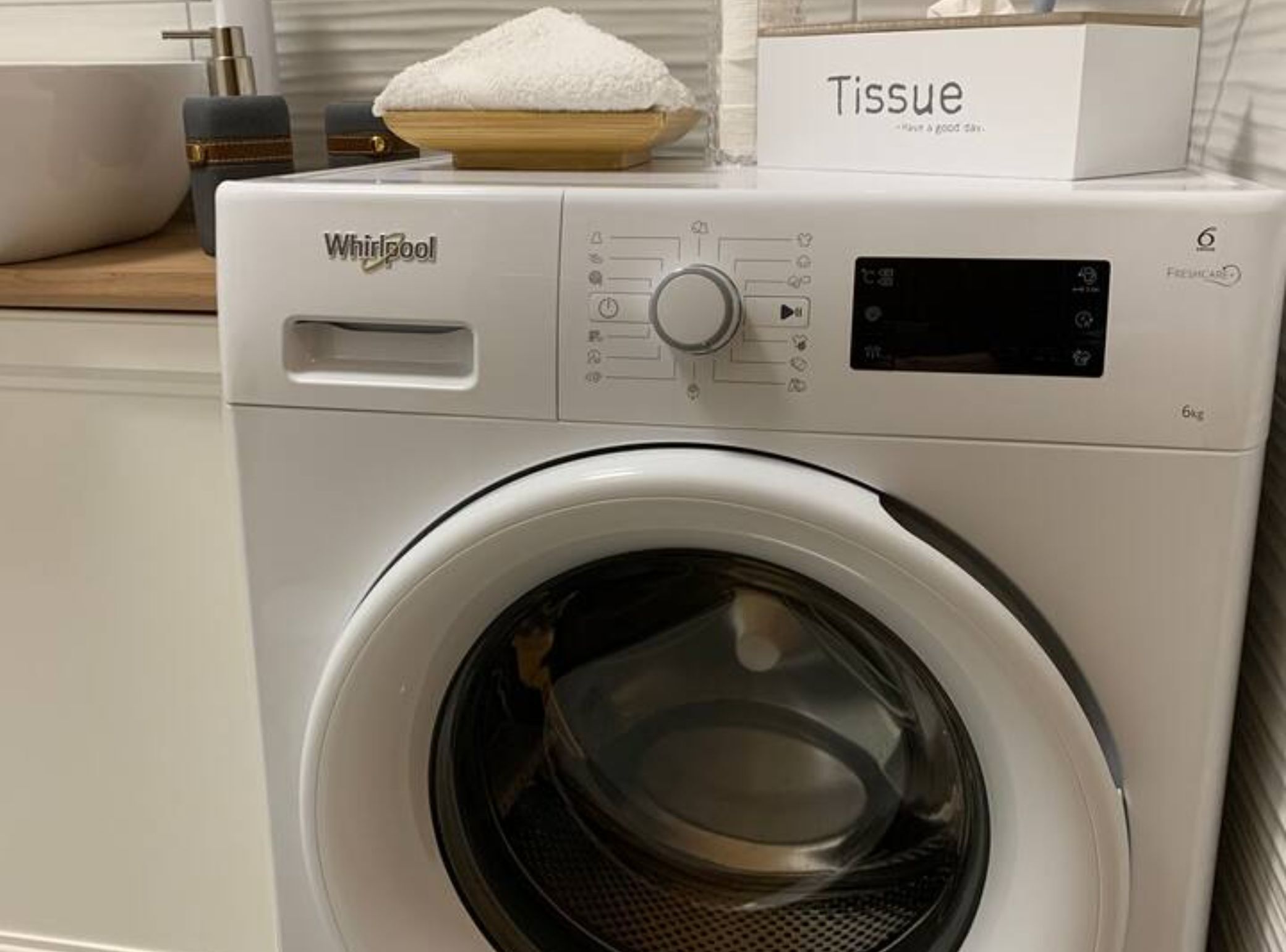 A front-loading Whirlpool washer with a control panel, a digital display, and a 6kg capacity label.