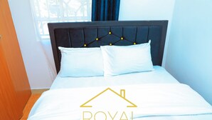 A hotel room with a bed, a headboard with a tufted design, and a window with curtains.