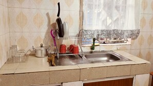 A kitchen with a sink, a dish rack, a window with a view, and a tiled backsplash.
