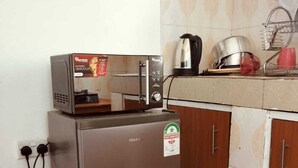 A compact kitchen with a refrigerator, a toaster, and a kettle on the countertop.