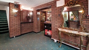 A lobby with brick walls, a reception desk, a mirror, and a vending machine. - Royal Oakwell Hotel (Blackpool)