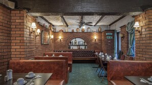 A restaurant with brick walls, leather booths, and tables set for dining. - Royal Oakwell Hotel (Blackpool)